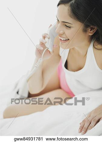 Close-up of a young woman lying down and using a telephone View Large Photo Image Stock Image - Close-up of a young woman lying down and using a telephone. Fotosearch
