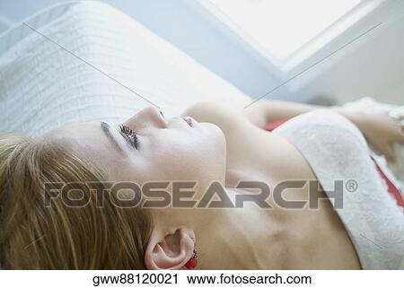 Stock Image - Close-up of a young woman lying on the bed. Fotosearch