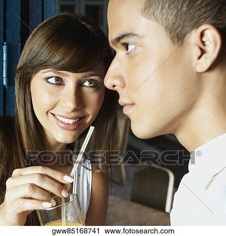 Close-up of a young woman offering a glass of juice to a young man View Large Photo Image Stock Image - Close-up of a young woman offering a glass of juice to a young man. Fotosearch