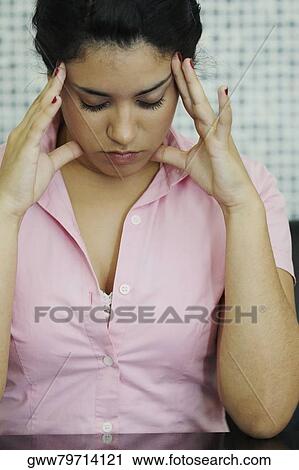 Stock Image - Close-up of a young woman rubbing her temples. Fotosearch