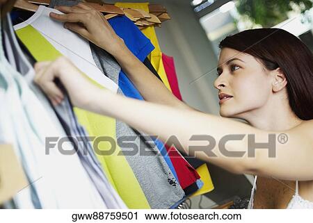 Close-up of a young woman selecting clothes in a clothing store View Large Photo Image Stock Image - Close-up of a young woman selecting clothes in a clothing store. Fotosearch