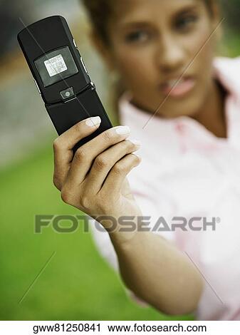 Stock Image - Close-up of a young woman taking a picture of herself with a mobile phone. Fotosearch