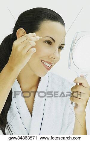 Close-up of a young woman tweezing her eyebrows and smiling View Large Photo Image Stock Image - Close-up of a young woman tweezing her eyebrows and smiling. Fotosearch