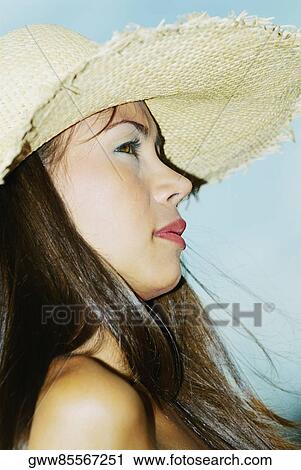 Stock Image - Close-up of a young woman wearing a sunhat. Fotosearch
