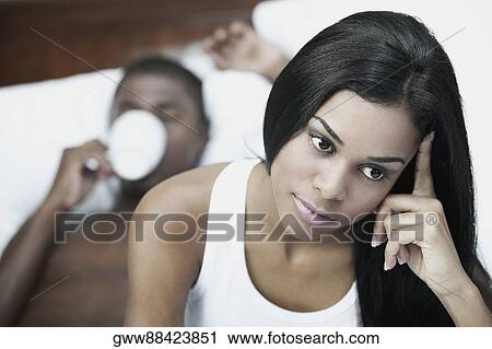 Close-up of a young woman with her head in her hand and a mid adult man lying in the background View Large Photo Image Stock Image - Close-up of a young woman with her head in her hand and a mid adult man lying in the background. Fotosearch