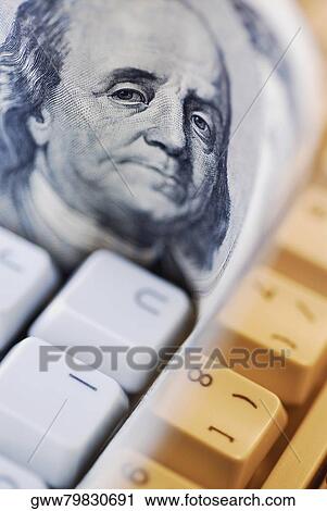 Stock Image - Close-up of one hundred dollar bill on a computer keyboard. Fotosearch