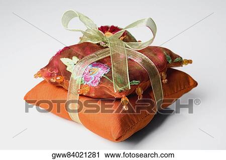 Stock Image - Close-up of two cushions wrapped with a ribbon. Fotosearch