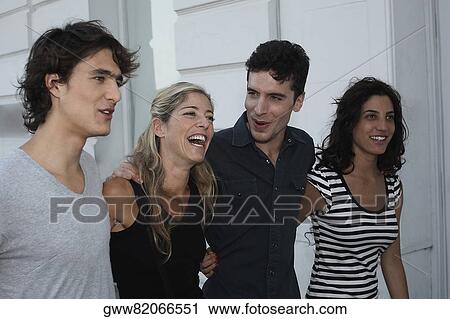 Stock Image - Close-up of two young couples walking with their arms around each other. Fotosearch