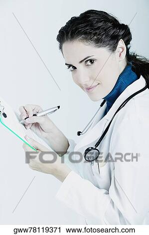 Stock Image - Female doctor writing on a clipboard. Fotosearch