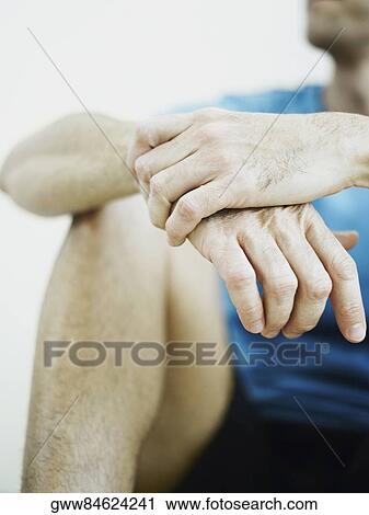 Stock Image - Front view of a person sitting and hugging knees. Fotosearch