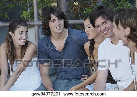 Group of friends sitting on a ledge View Large Photo Image Stock Image - Group of friends sitting on a ledge. Fotosearch