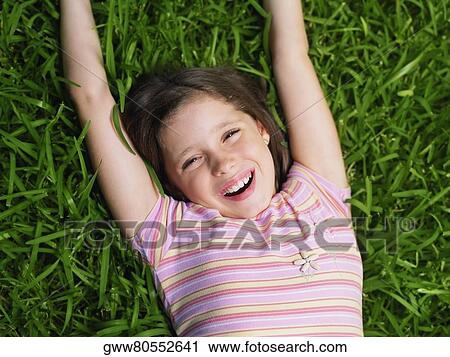 Stock Image - High angle view of a girl lying on the grass. Fotosearch