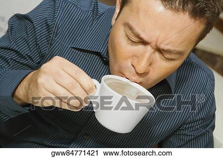 Stock Image - High angle view of a mid adult man drinking a cup of tea in a restaurant. Fotosearch