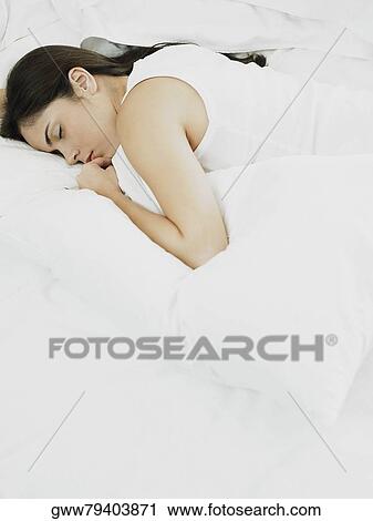 High angle view of a young woman lying on the bed and holding a pillow View Large Photo Image Stock Image - High angle view of a young woman lying on the bed and holding a pillow. Fotosearch