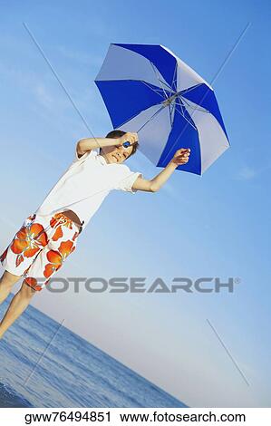 Low angle view of a boy jumping with an umbrella View Large Photo Image Stock Image - Low angle view of a boy jumping with an umbrella. Fotosearch