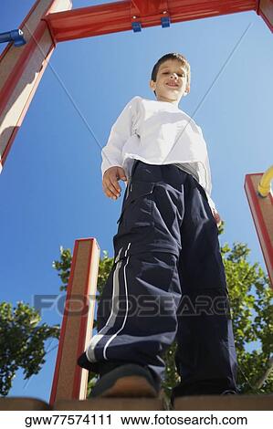 Low angle view of a boy smiling and standing on a jungle gym View Large Photo Image Stock Image - Low angle view of a boy smiling and standing on a jungle gym. Fotosearch