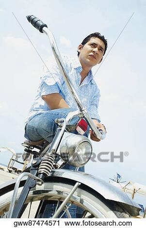 Low angle view of a mid adult man sitting on a bicycle View Large Photo Image Stock Image - Low angle view of a mid adult man sitting on a bicycle. Fotosearch
