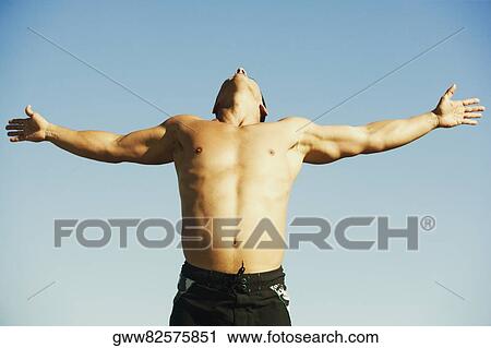 Stock Image - Low angle view of a mid adult man with his arms outstretched. Fotosearch