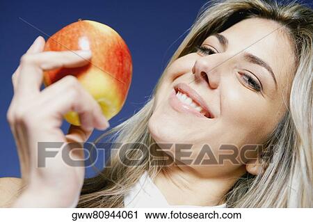 Low angle view of a mid adult woman holding an apple and smiling View Large Photo Image Stock Image - Low angle view of a mid adult woman holding an apple and smiling. Fotosearch