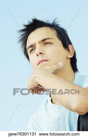 Low angle view of a young man thinking View Large Photo Image Stock Image - Low angle view of a young man thinking. Fotosearch