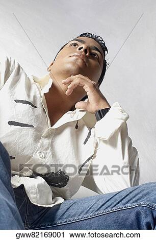 Low angle view of a young man thinking View Large Photo Image Stock Image - Low angle view of a young man thinking. Fotosearch