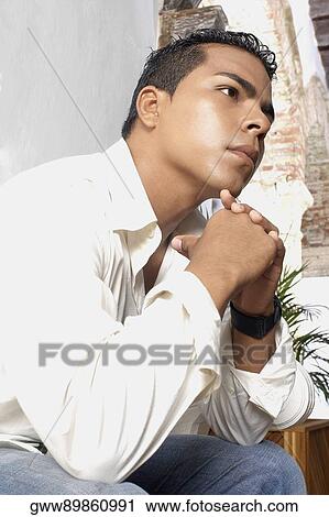 Low angle view of a young man thinking View Large Photo Image Stock Image - Low angle view of a young man thinking. Fotosearch