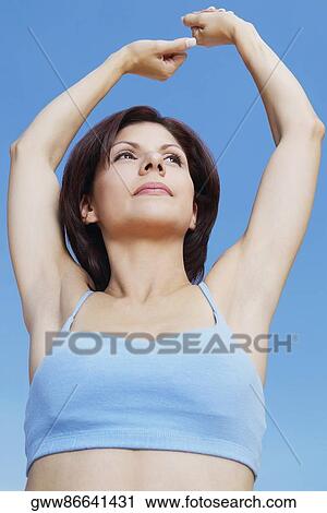 Low angle view of a young woman stretching her arms View Large Photo Image Stock Image - Low angle view of a young woman stretching her arms. Fotosearch