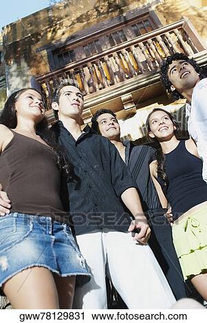 Low angle view of five friends standing and smiling View Large Photo Image Stock Image - Low angle view of five friends standing and smiling. Fotosearch