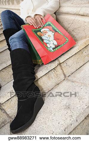 Low section view of a woman sitting on steps with shopping bags View Large Photo Image Stock Image - Low section view of a woman sitting on steps with shopping bags. Fotosearch