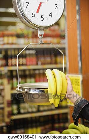 Man's hand weighing a bunch of bananas on a weighing scale in a supermarket View Large Photo Image Stock Image - Man's hand weighing a bunch of bananas on a weighing scale in a supermarket. Fotosearch