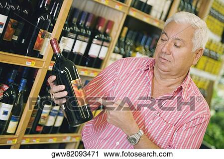 Mature man holding a bottle of wine View Large Photo Image Stock Image - Mature man holding a bottle of wine. Fotosearch