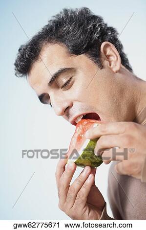 Mid adult man eating a watermelon slice View Large Photo Image Stock Image - Mid adult man eating a watermelon slice. Fotosearch