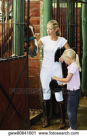 Mid adult woman and her daughter standing in a stable View Large Photo Image Stock Image - Mid adult woman and her daughter standing in a stable. Fotosearch