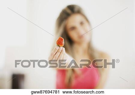 Mid adult woman showing a strawberry View Large Photo Image Stock Image - Mid adult woman showing a strawberry. Fotosearch