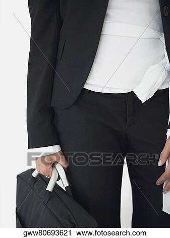 Mid section view of a businesswoman standing and holding a bag View Large Photo Image Stock Image - Mid section view of a businesswoman standing and holding a bag. Fotosearch