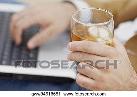 Mid section view of a man using a laptop and holding a glass of wine View Large Photo Image Stock Image - Mid section view of a man using a laptop and holding a glass of wine. Fotosearch