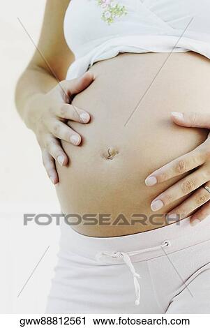 Mid section view of a pregnant woman touching her abdomen View Large Photo Image Stock Image - Mid section view of a pregnant woman touching her abdomen. Fotosearch