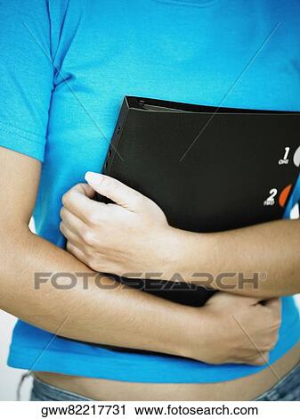 Mid section view of a woman holding a file View Large Photo Image Stock Image - Mid section view of a woman holding a file. Fotosearch