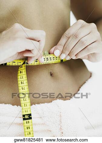 Mid section view of a woman measuring her waist with a tape measure View Large Photo Image Stock Image - Mid section view of a woman measuring her waist with a tape measure. Fotosearch