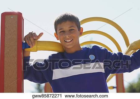 Stock Image - Portrait of a boy holding monkey bars. Fotosearch