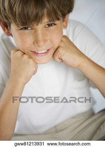 Stock Image - Portrait of a boy smiling with his hand on his chin. Fotosearch