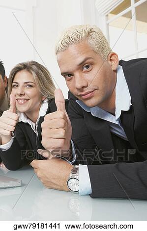 Stock Image - Portrait of a businessman and a businesswoman showing thumbs up signs . Fotosearch