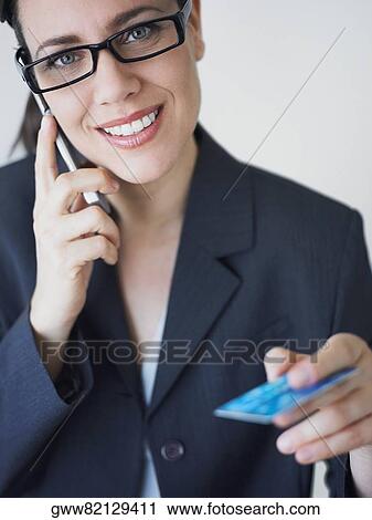 Portrait of a businesswoman talking on a mobile phone and holding a credit card View Large Photo Image Stock Image - Portrait of a businesswoman talking on a mobile phone and holding a credit card. Fotosearch