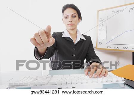 Portrait of a businesswoman using a computer keyboard and pointing forward View Large Photo Image Stock Image - Portrait of a businesswoman using a computer keyboard and pointing forward. Fotosearch