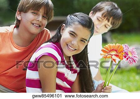 Stock Image - Portrait of a girl holding flowers and smiling with her friends. Fotosearch