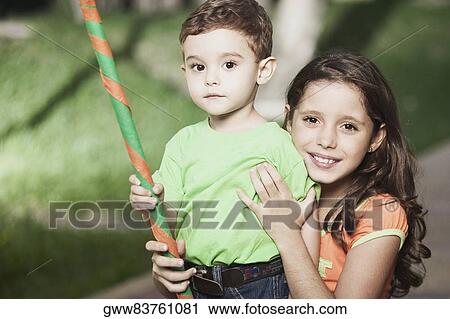 Portrait of a girl smiling and her brother holding a stick View Large Photo Image Stock Image - Portrait of a girl smiling and her brother holding a stick. Fotosearch