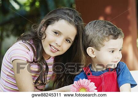 Stock Image - Portrait of a girl smiling with a boy beside her. Fotosearch