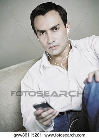Stock Image - Portrait of a mature man listening to an MP3 player. Fotosearch