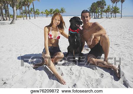 Portrait of a mid adult man and a young woman sitting with their dog on the beach View Large Photo Image Stock Image - Portrait of a mid adult man and a young woman sitting with their dog on the beach. Fotosearch
