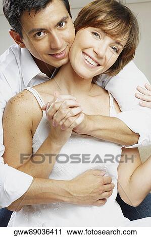 Portrait of a mid adult man embracing a young woman from behind View Large Photo Image Stock Image - Portrait of a mid adult man embracing a young woman from behind. Fotosearch